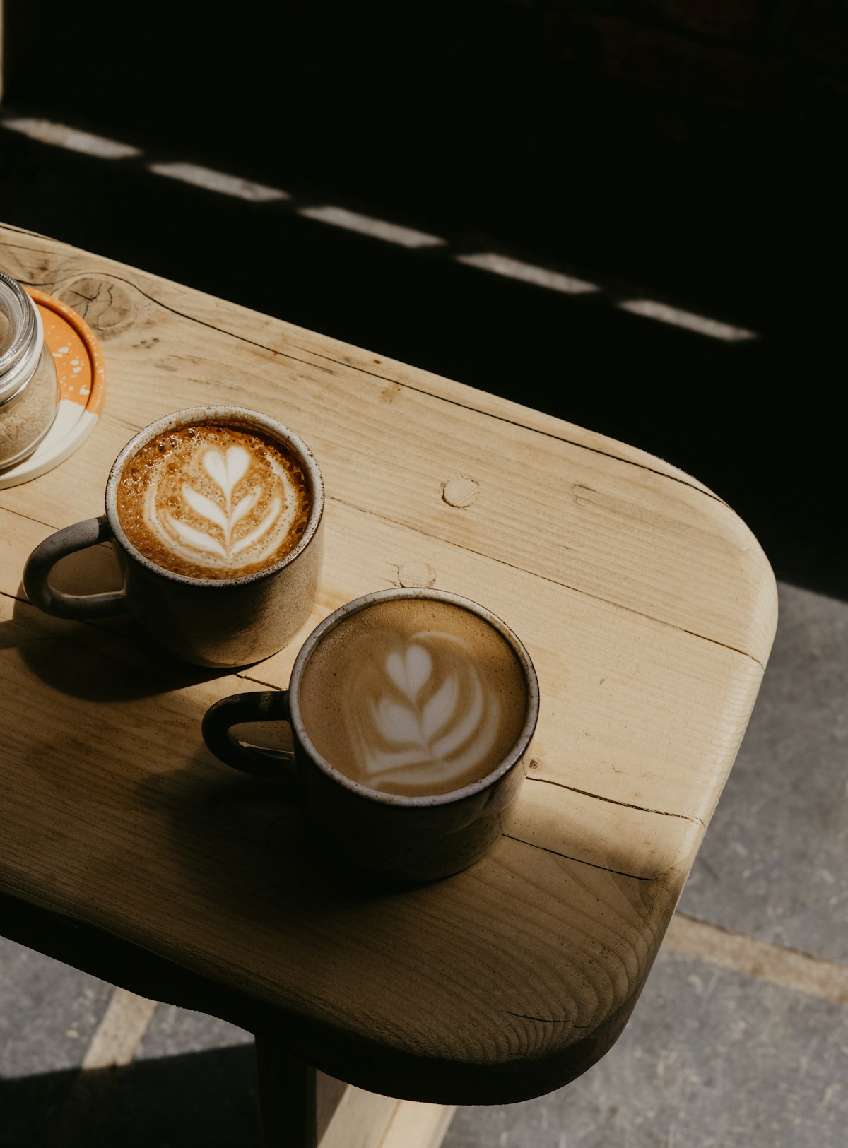Two coffees shared at a sunlit café table