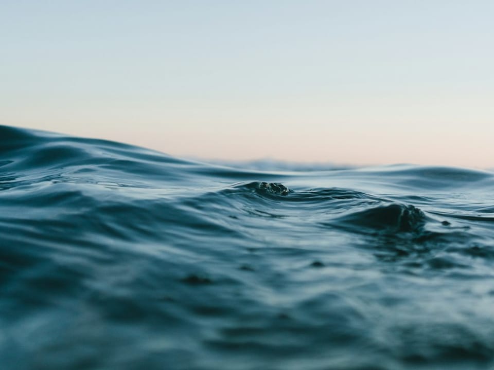 A quiet blue sea meeting the evening sky